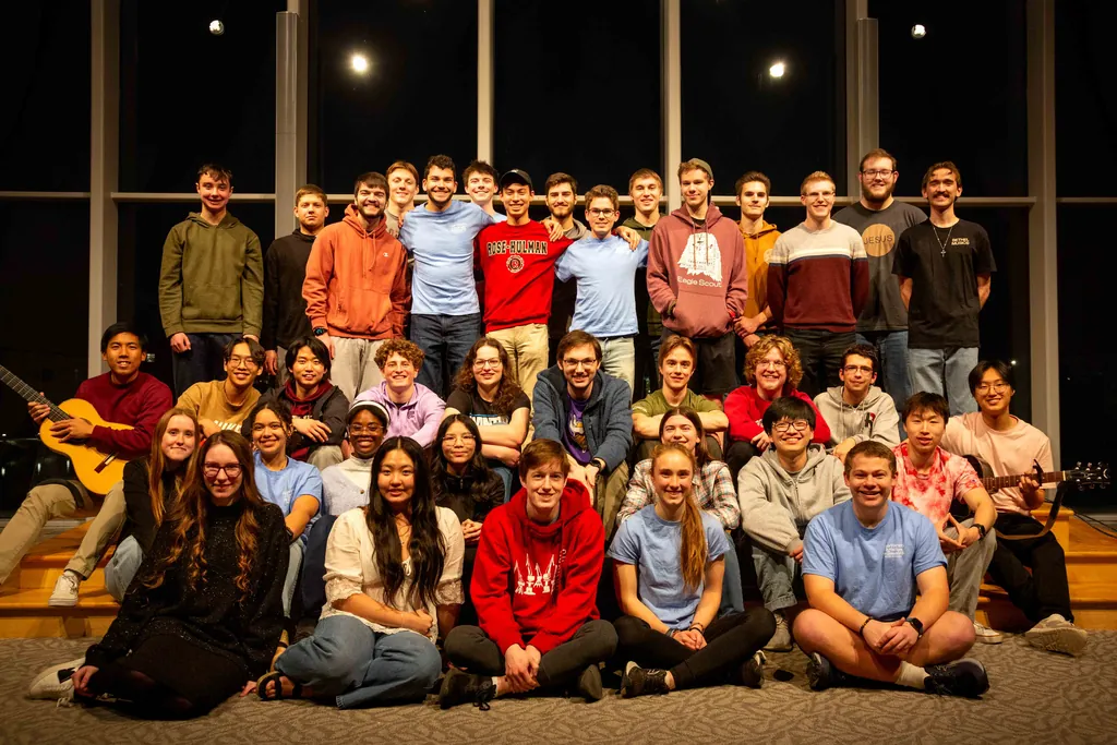 A large group of students gathered on and around a stage after an InterVarsity meeting.